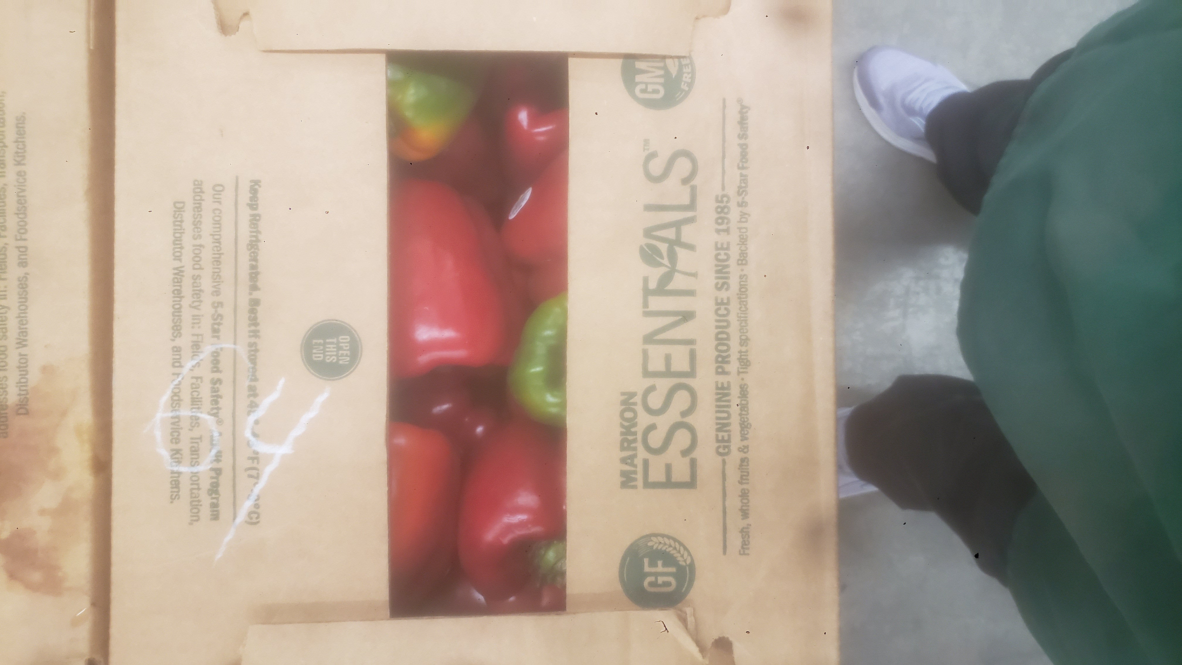Cardboard box with green and red bell pepper peeking out.